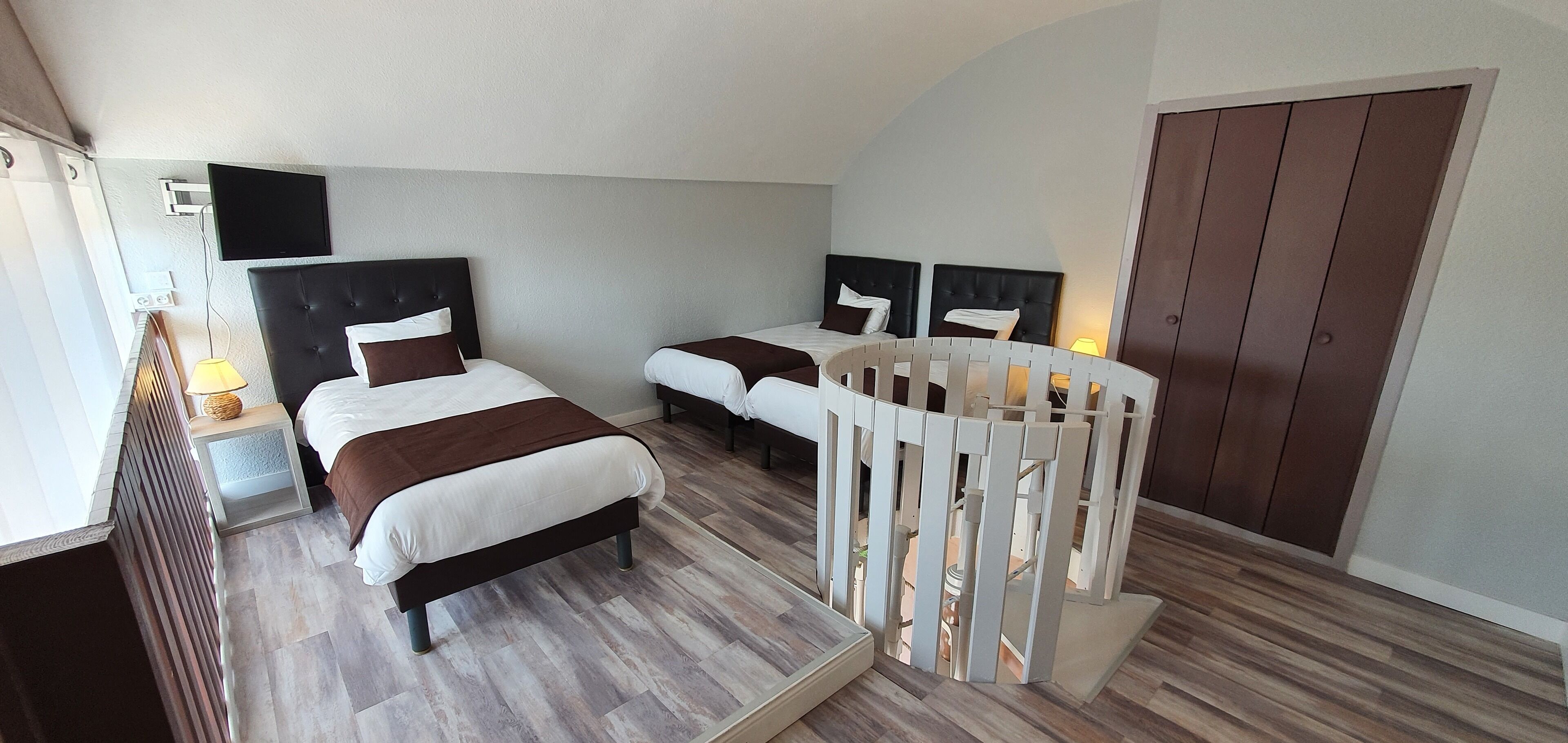 Hotellihuone, jossa on kaksi sänkyä, televisio, puulattia ja vaatekaappi.