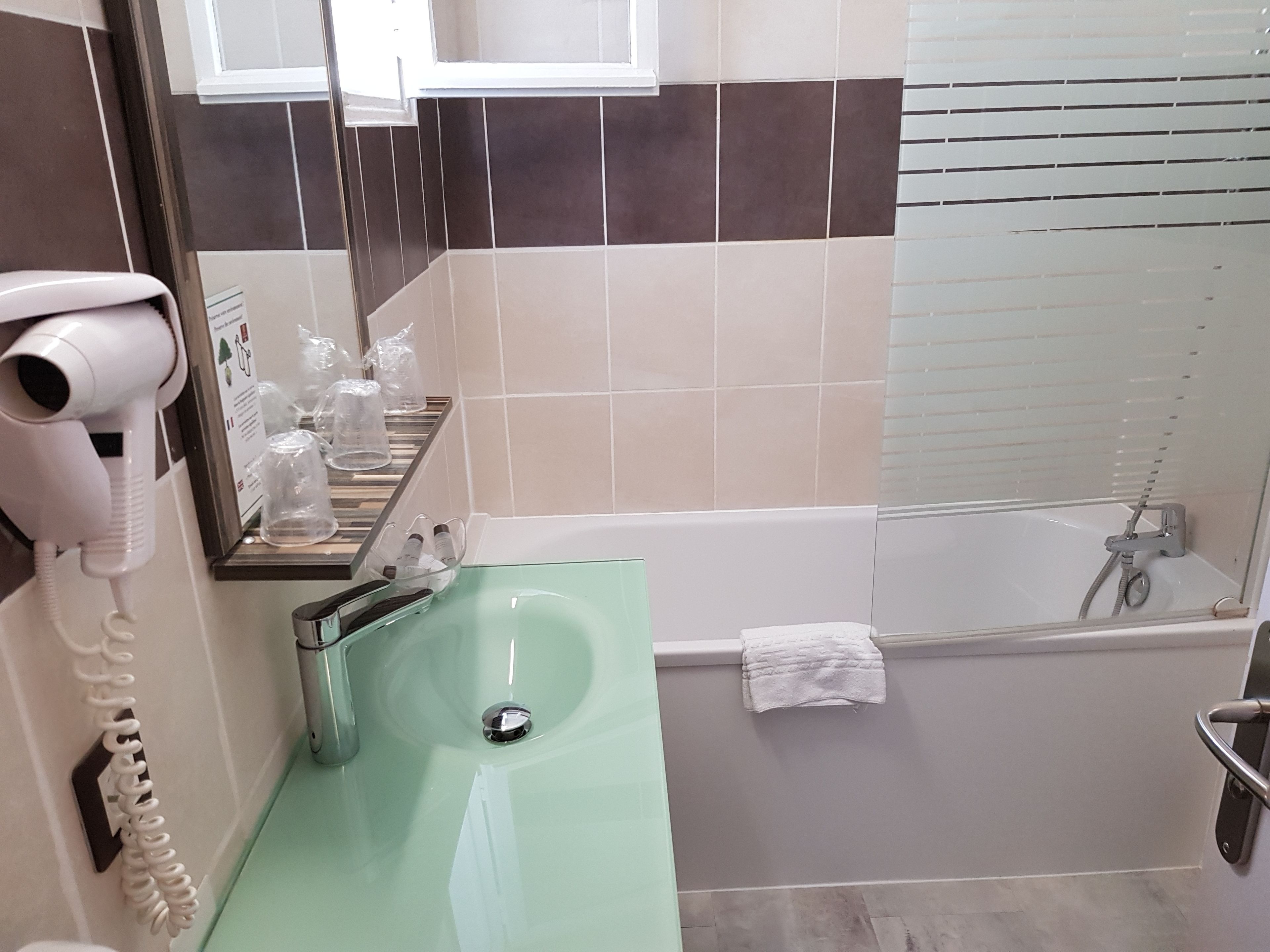 A bathroom with a sink, mirror, and a hairdryer on the wall.