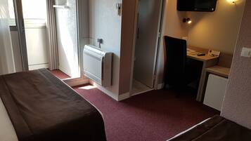 Habitación de hotel con dos camas, un escritorio pequeño, televisión y calefacción.