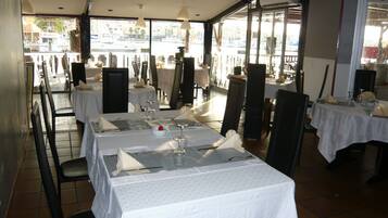 Un restaurant avec des tables dressées, de grandes fenêtres et une vue sur la rue.