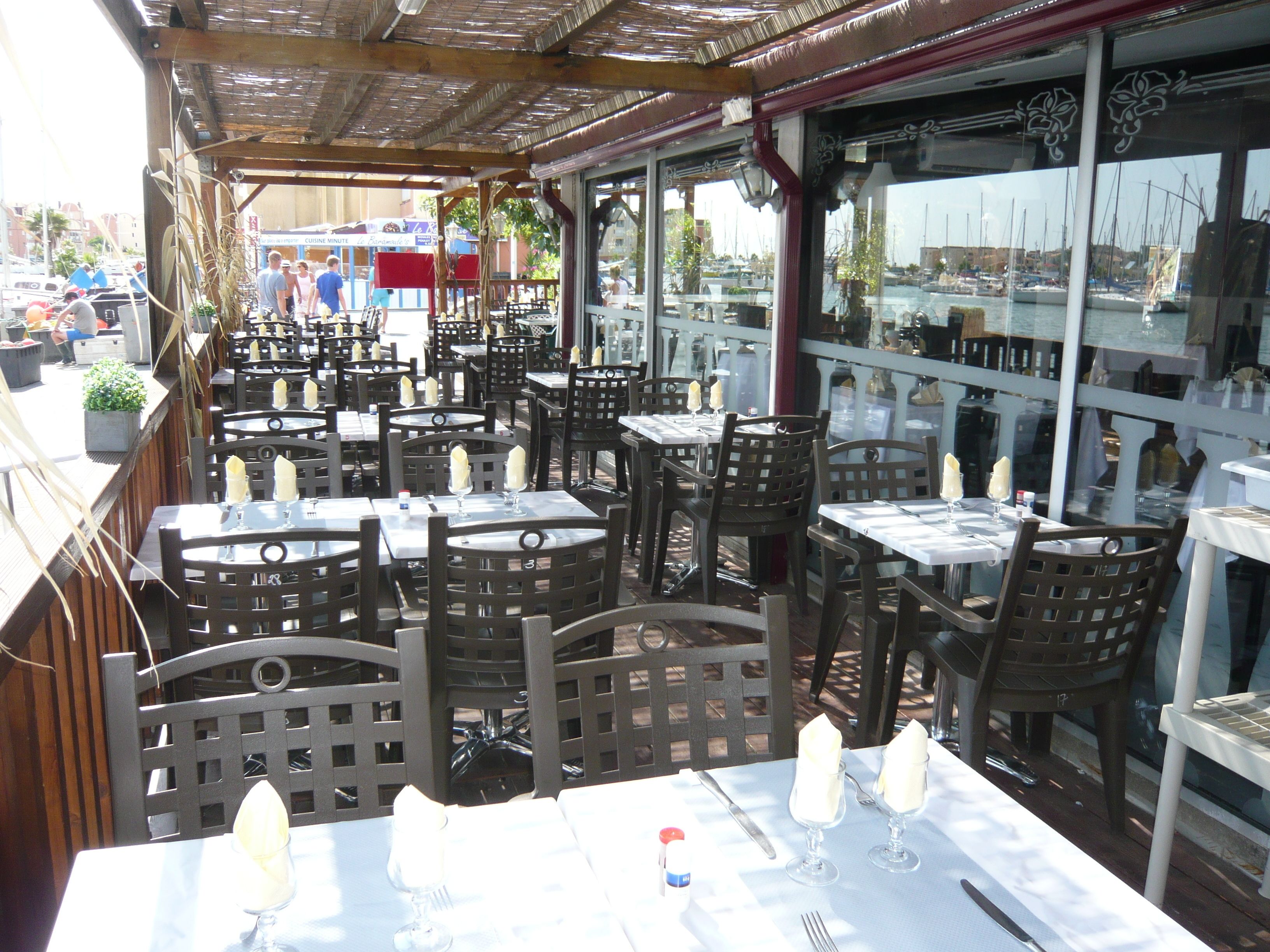 An outdoor dining area with multiple tables and chairs, some with candles.