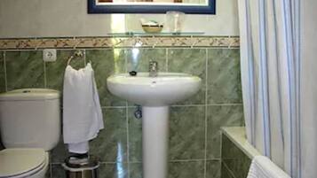 A bathroom with a toilet, sink, and a mirror above the sink.