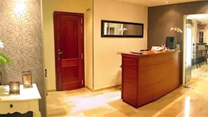 Uma área de recepção com uma mesa de madeira, um espelho e uma porta.
