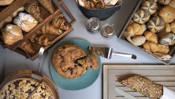 A variety of baked goods including bread, pastries, and a pie on a table.