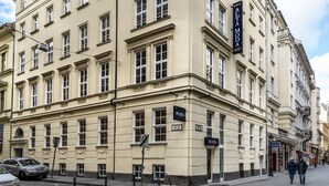 En bygning i flere etager med klassisk arkitektur, der har et tydeligt skilt for 'Altamoda' på facaden.