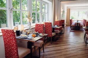 Un restaurante con un amplio comedor, sillas rojas con estampado y vistas a la vegetación a través de amplios ventanales.