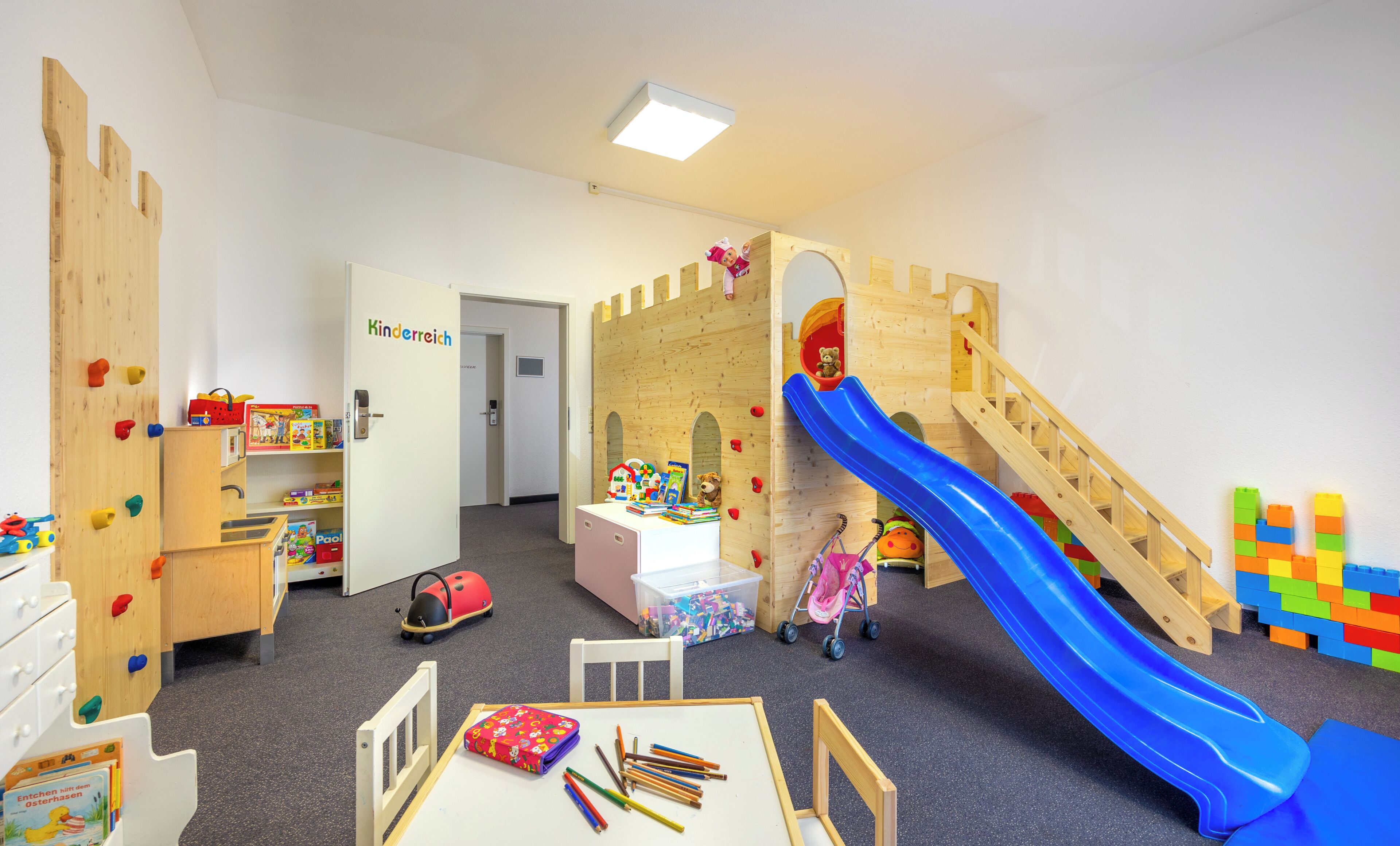 Una sala de juegos infantiles con tobogán, pared de escalada y varios juguetes.