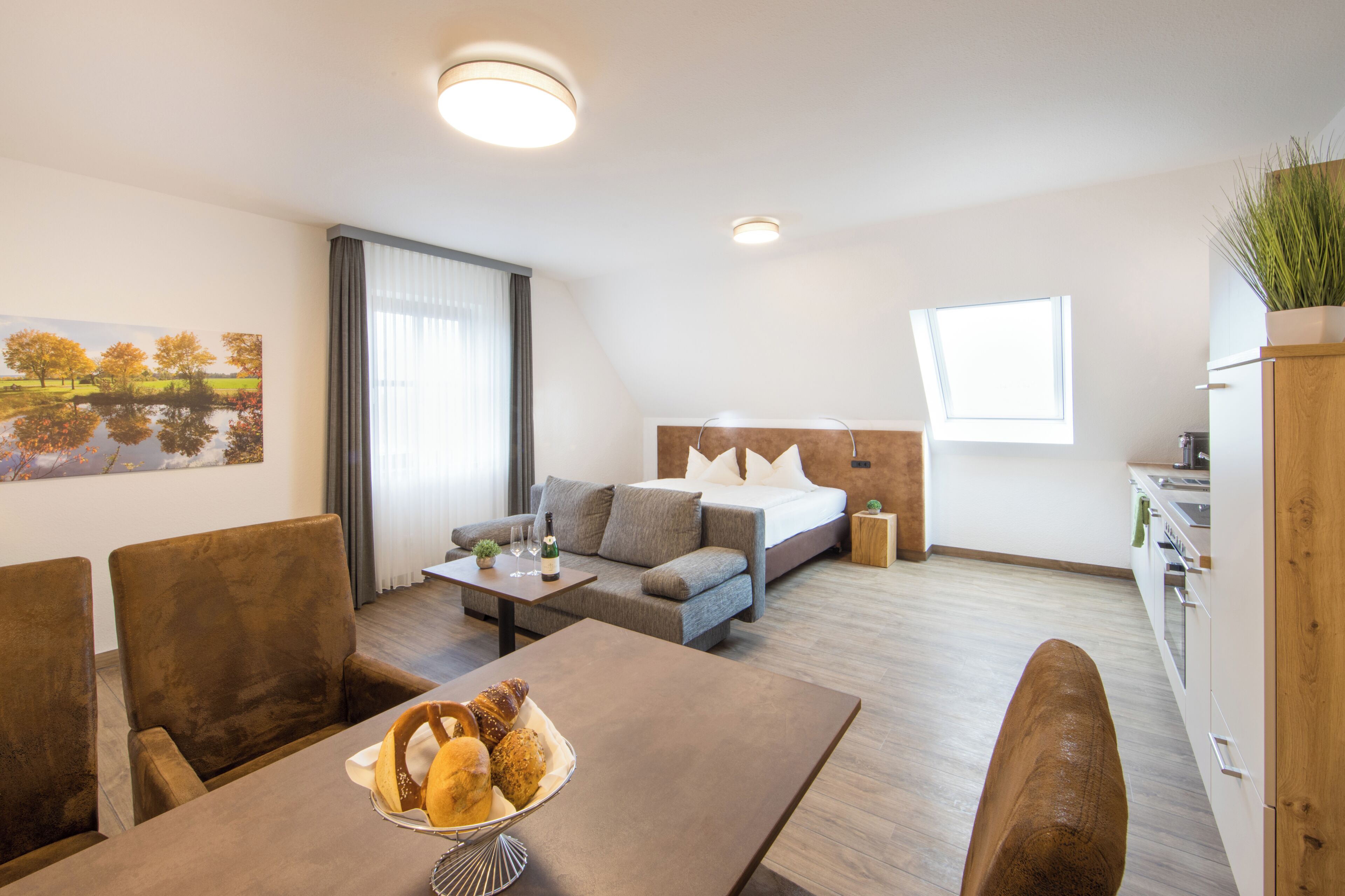 A modern living room with a sofa, a dining table with bread, and a kitchen area.