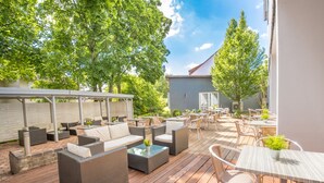 An outdoor patio area with wicker furniture, a covered seating area, and a view of a building in the background. - Hotel Am Kurpark Späth (Bad Windsheim)