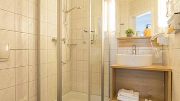 Ein modernes Badezimmer mit einer Duschkabine, einer Toilette und einem Waschtisch mit Spiegel.