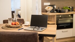 A modern kitchen with a laptop on a wooden table, a vase, and two apples. - Hotel Am Kurpark Späth (Bad Windsheim)