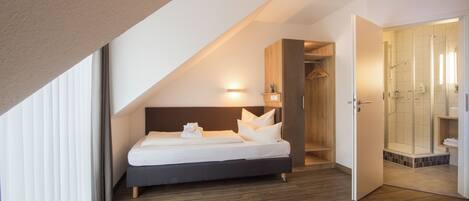 A modern bedroom with a bed, a wooden wardrobe, and a shower area.
