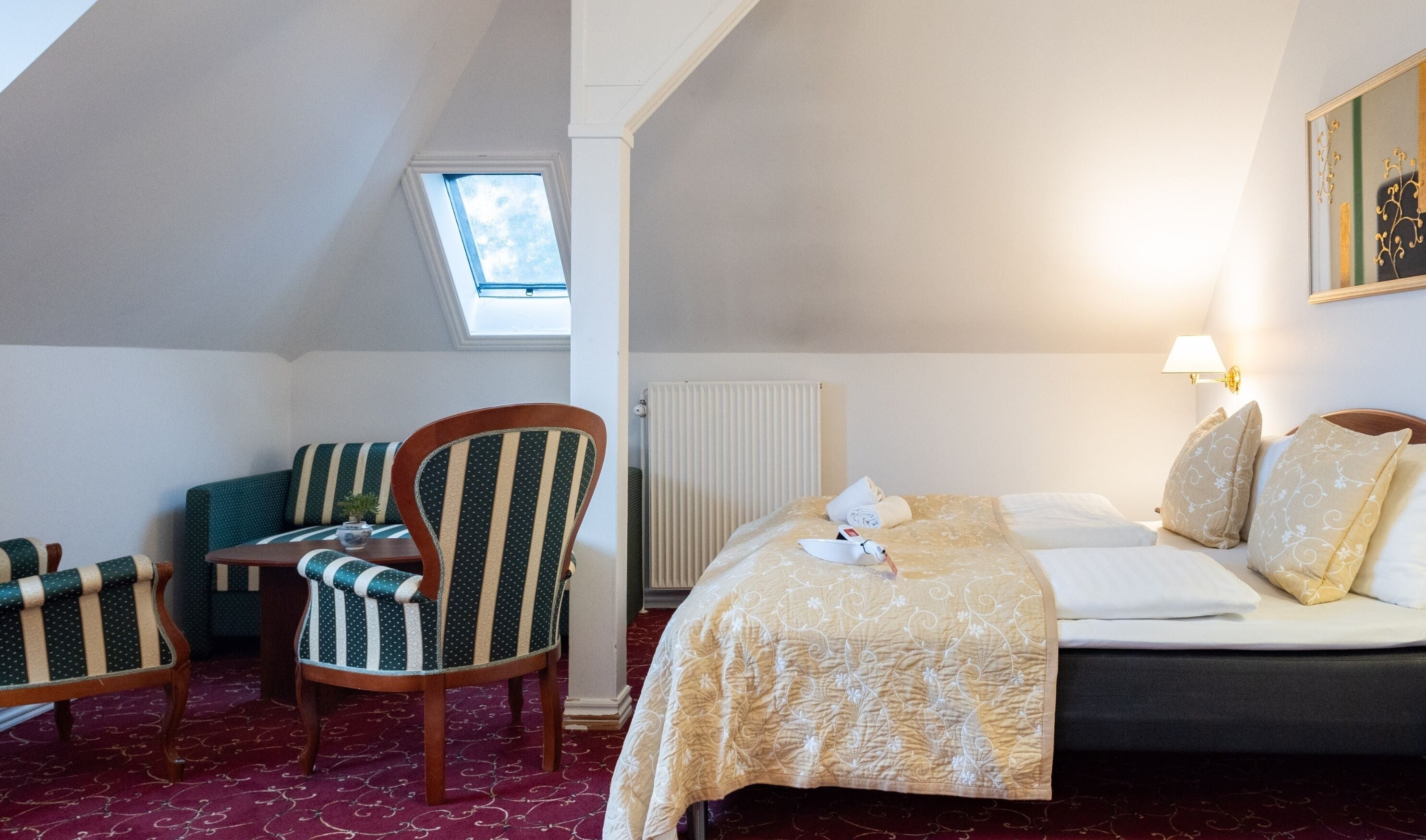 Ein Hotelzimmer mit Bett, einem Sessel, einem kleinen Tisch und einer Heizung.