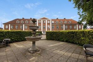 A courtyard with a fountain, outdoor seating, and a large brick building with a symmetrical facade. - Milling Hotel Park (Middelfart)