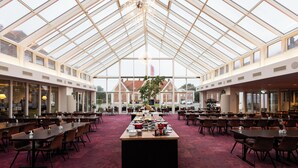 A spacious hall with a high ceiling and large windows, featuring a central buffet table and numerous seating arrangements. - Milling Hotel Park (Middelfart)