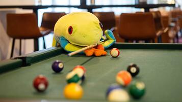 Una mesa de billar con un peluche y bolas de billar.