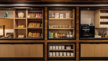 Mostrador de panadería con diversos productos horneados, botes de mermeladas y una máquina de café.
