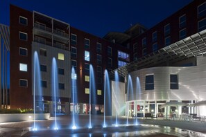 A building with multiple floors, a courtyard with fountains, and outdoor seating areas. - Domina Milano Fiera (Novate Milanese)