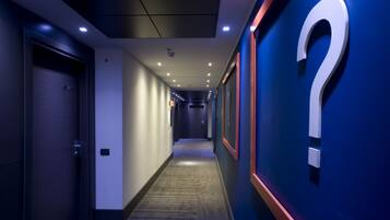 A modern hotel corridor with a question mark on the wall, indicating a possible mystery or unknown feature.