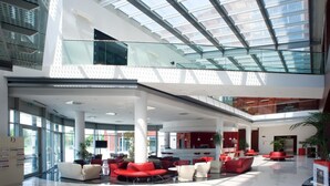 A spacious lobby with a high ceiling, glass railings, and multiple seating areas. - Domina Milano Fiera (Novate Milanese)
