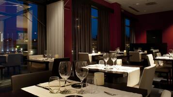 Un ristorante con tavoli apparecchiati, con vista panoramica attraverso ampie finestre.