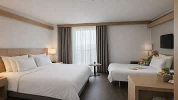 Une chambre d’hôtel avec deux lits, un bureau, une télévision et une fenêtre avec des rideaux.