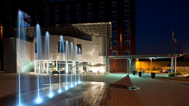 A hotel entrance with a water feature and outdoor seating area. - Domina Milano Fiera (Novate Milanese)
