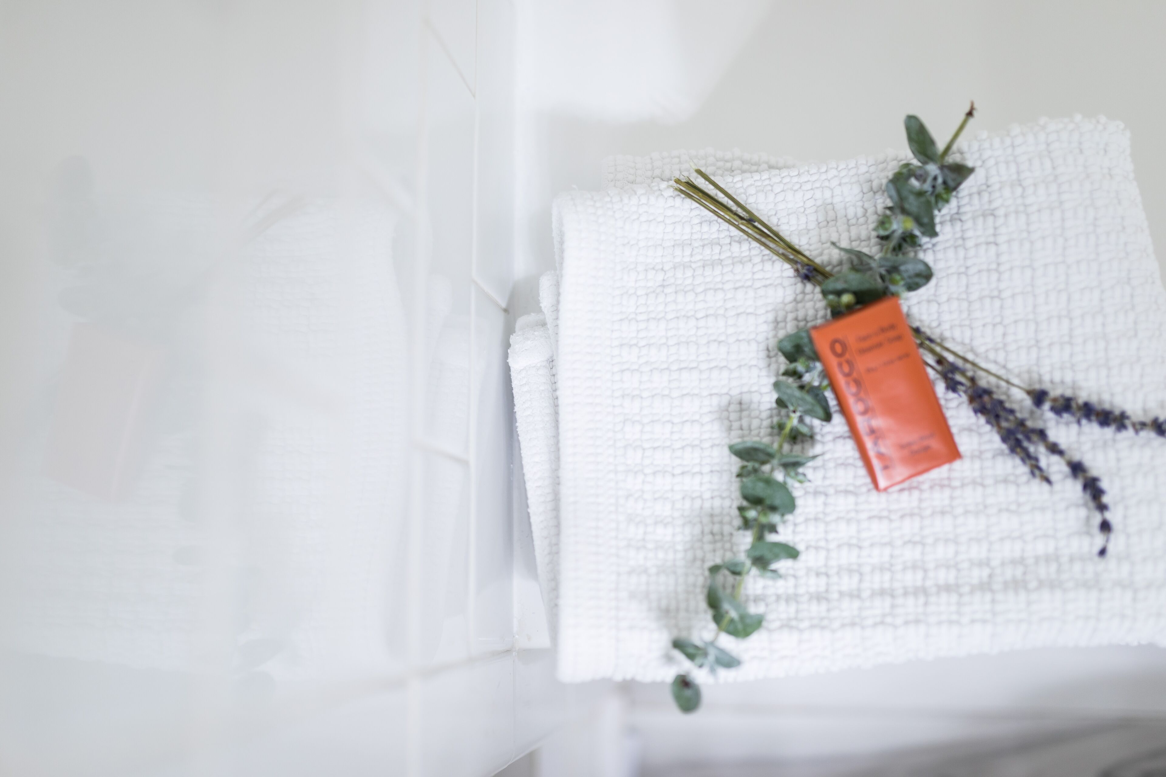 A white towel with a tag and dried lavender on a textured surface.