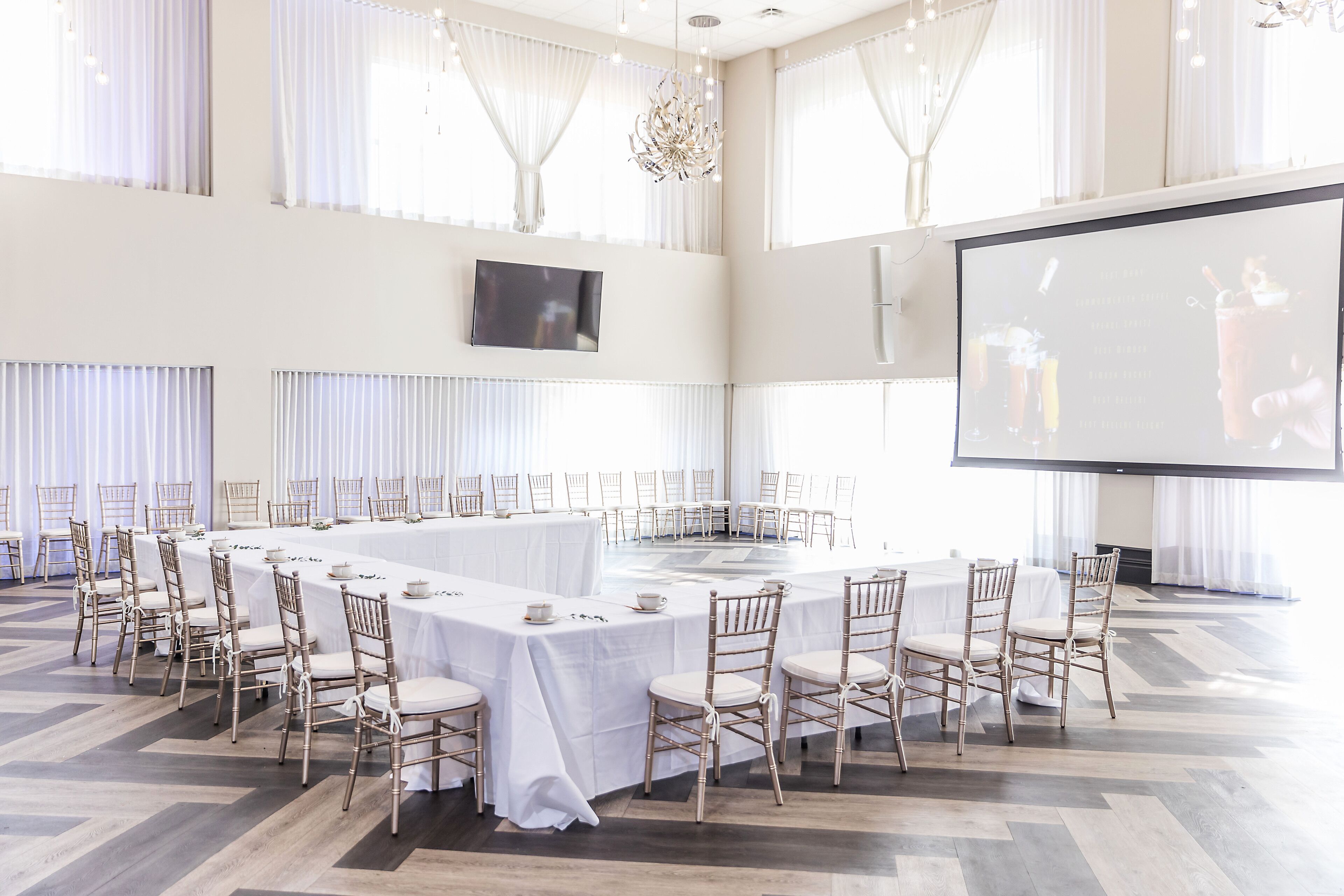 A conference room with a long table, chairs, a screen, and a chandelier.
