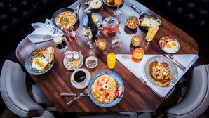 A breakfast table with various dishes, drinks, and a bottle of wine. - The Lodge at Kiln Creek Resort (Newport News)