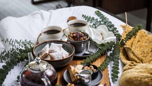 A neatly arranged breakfast table with tea, pastries, and a notepad, set against a backdrop of a wooden desk and a chair. - The Lodge at Kiln Creek Resort (Newport News)