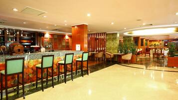 A bar area with a counter, stools, and a decorative wall.