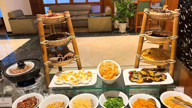 Een buffet met diverse gerechten, waaronder pinda's, tofu en augurken.