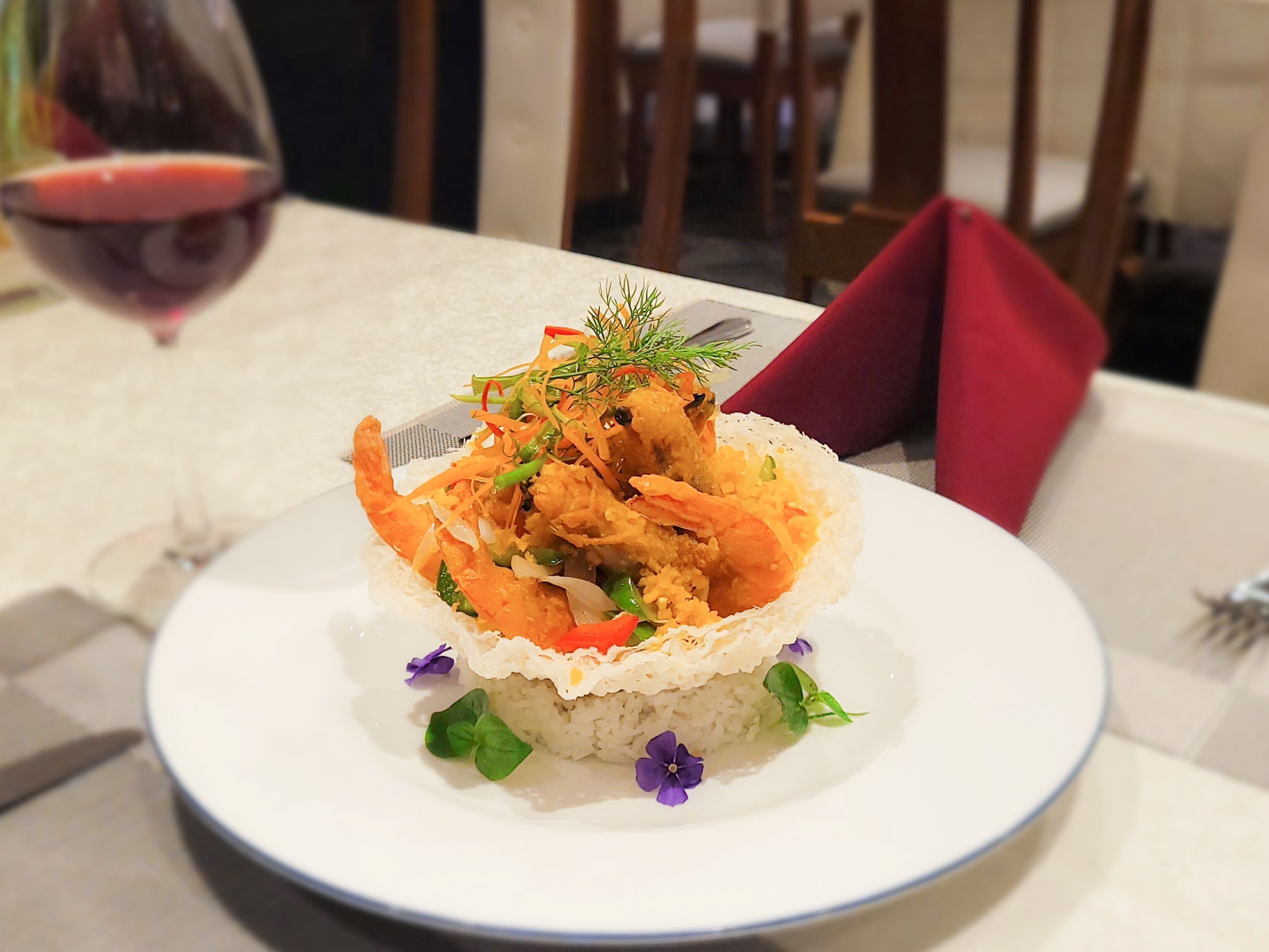 A plate of food with rice and vegetables, garnished with herbs, on a white plate.