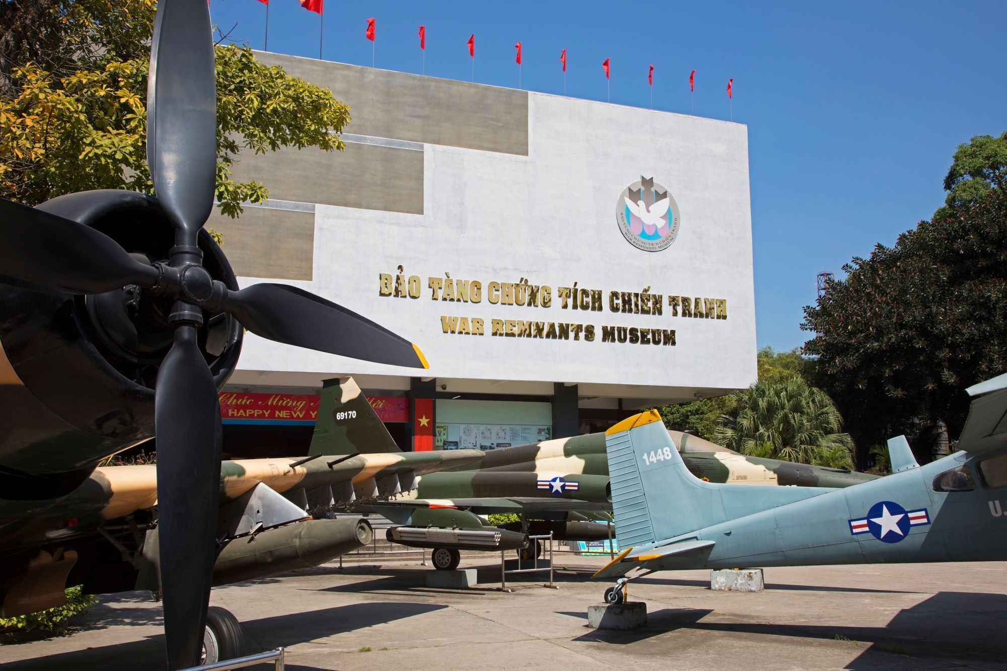 Ein Kriegerdenkmal mit einem großen Schild und mehreren ausgestellten Militärflugzeugen.