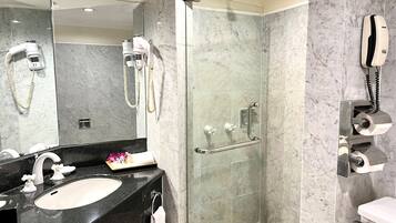 A modern bathroom with a glass-enclosed shower, a sink with a marble countertop, and a mirror.