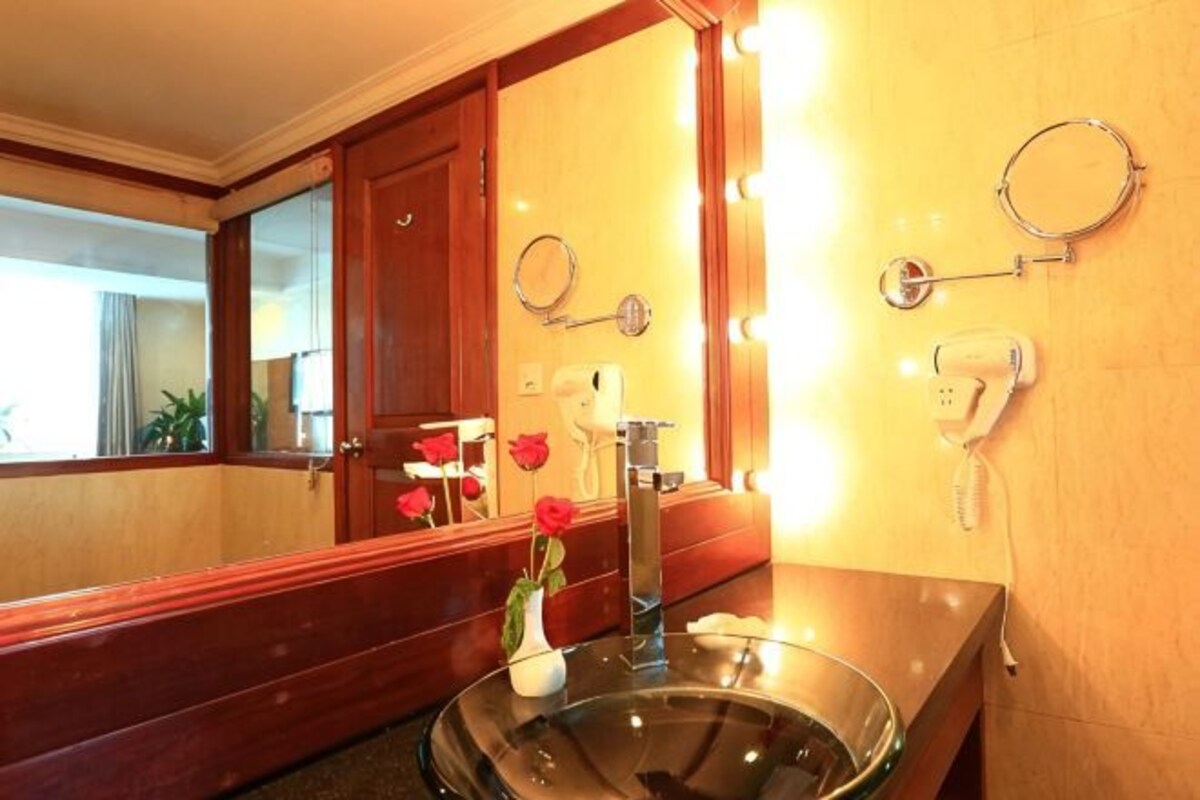 A bathroom with a large mirror, a glass sink, and two hair dryers mounted on the wall.