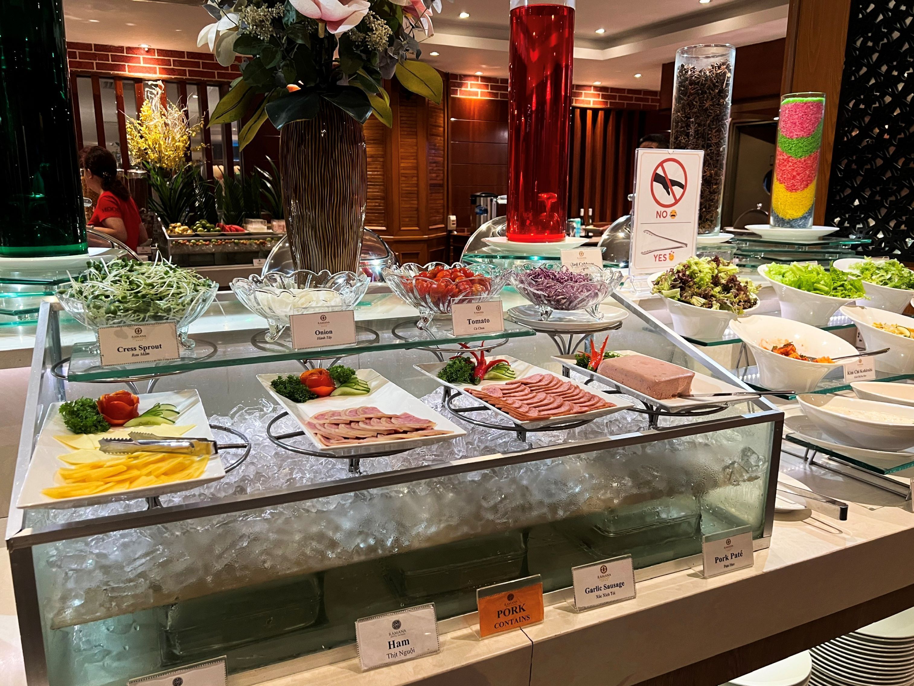 A buffet with various food items including cress sprout, tomato, onion, ham, and pork.