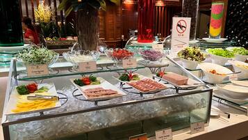 A buffet with various food items including cress sprout, tomato, onion, ham, and pork.