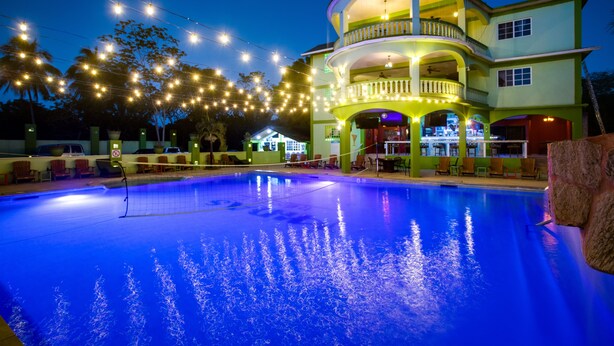 A pool area with a multi-level building, string lights, and outdoor seating.
