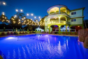 A pool area with a multi-level building, string lights, and outdoor seating.