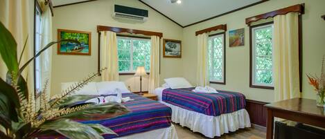 A room with two beds, a ceiling fan, an air conditioner, and large windows with curtains.