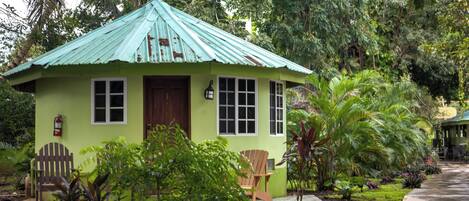 A small, single-story house with a green roof and a porch.