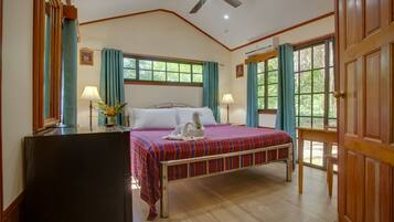 A bedroom with a bed, two bedside lamps, a ceiling fan, and a window with curtains.