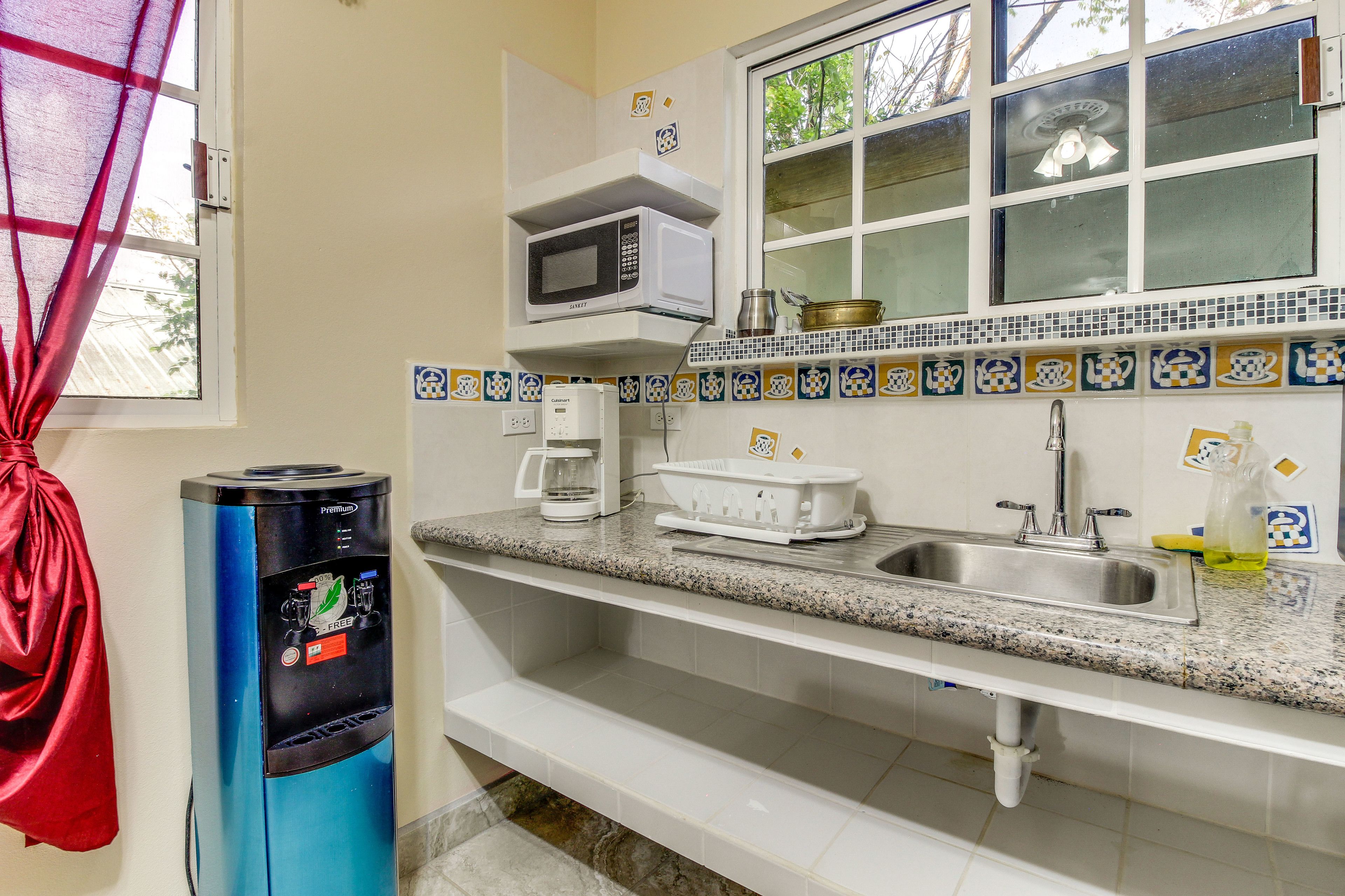 A kitchen with a microwave, coffee maker, sink, and a water dispenser.