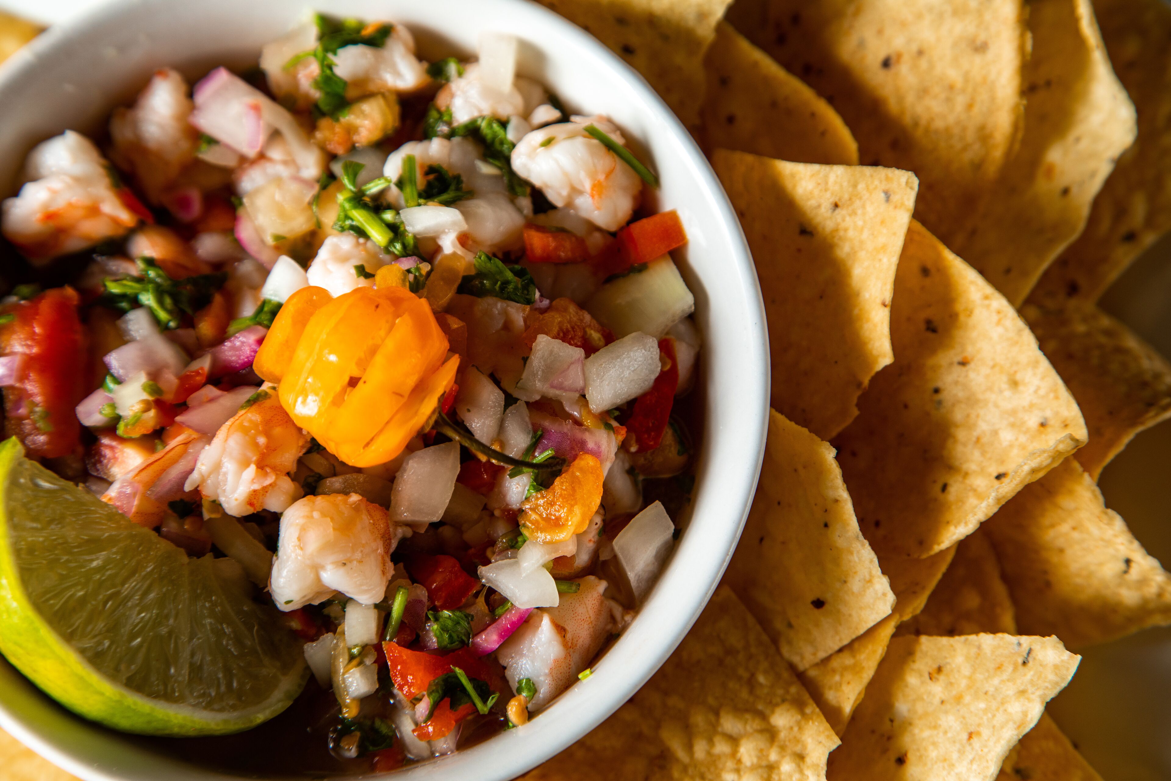 Uma tigela de ceviche de camarão com limão e tortilhas.