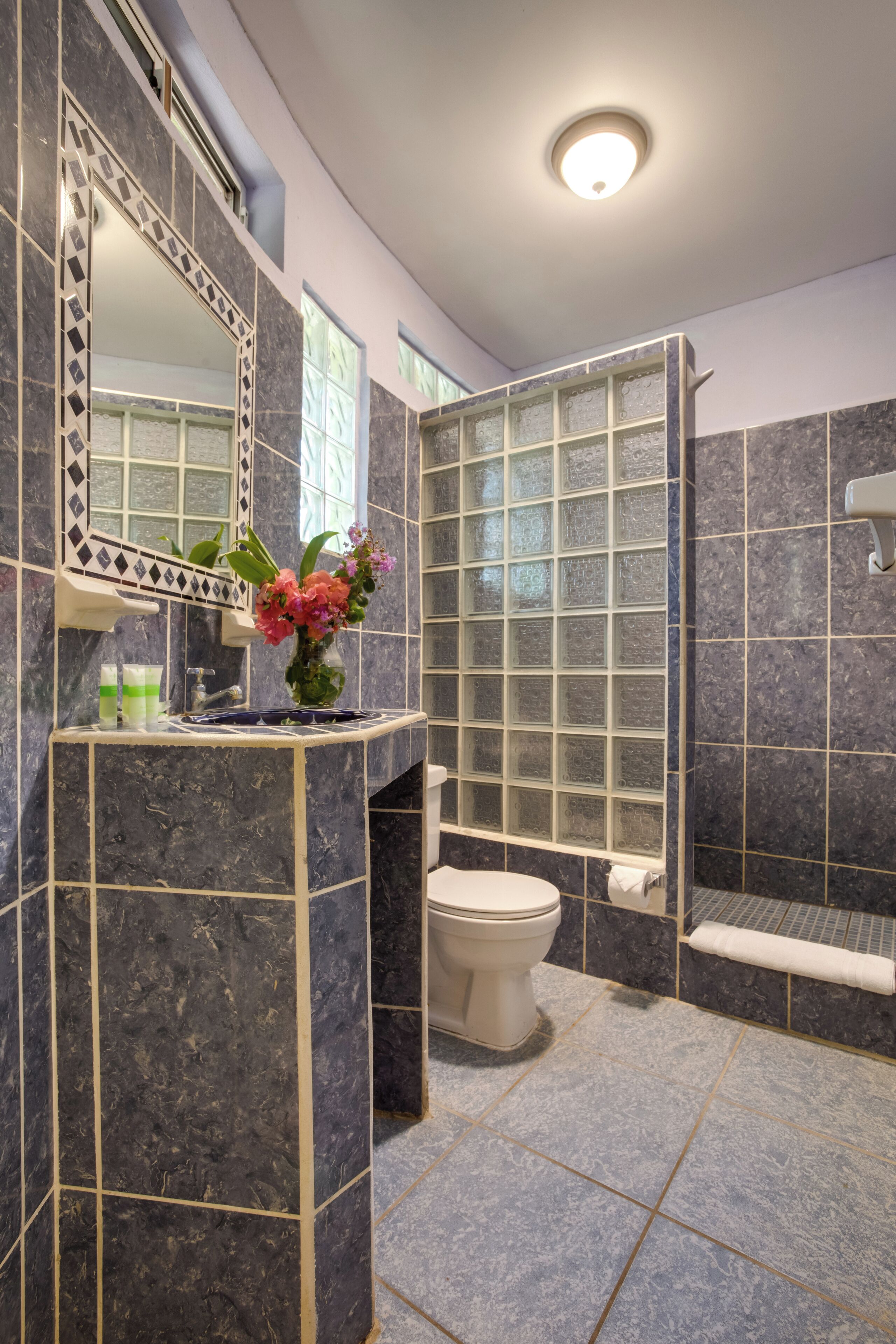 A bathroom with a marble vanity, a glass shower enclosure, and a toilet.