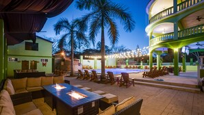 An outdoor patio with a fire pit, lounge seating, and a pool area.