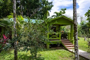 A green gazebo with a staircase leading up to it, surrounded by lush greenery and trees.