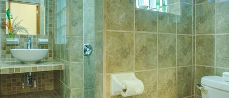 Un baño con lavamanos, espejo, inodoro, ducha y ventana con vistas.
